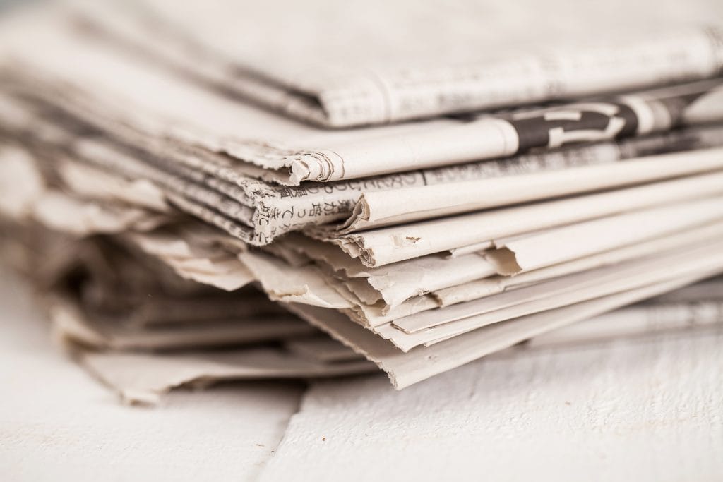 Pile of black and white newspapers on a wooden table