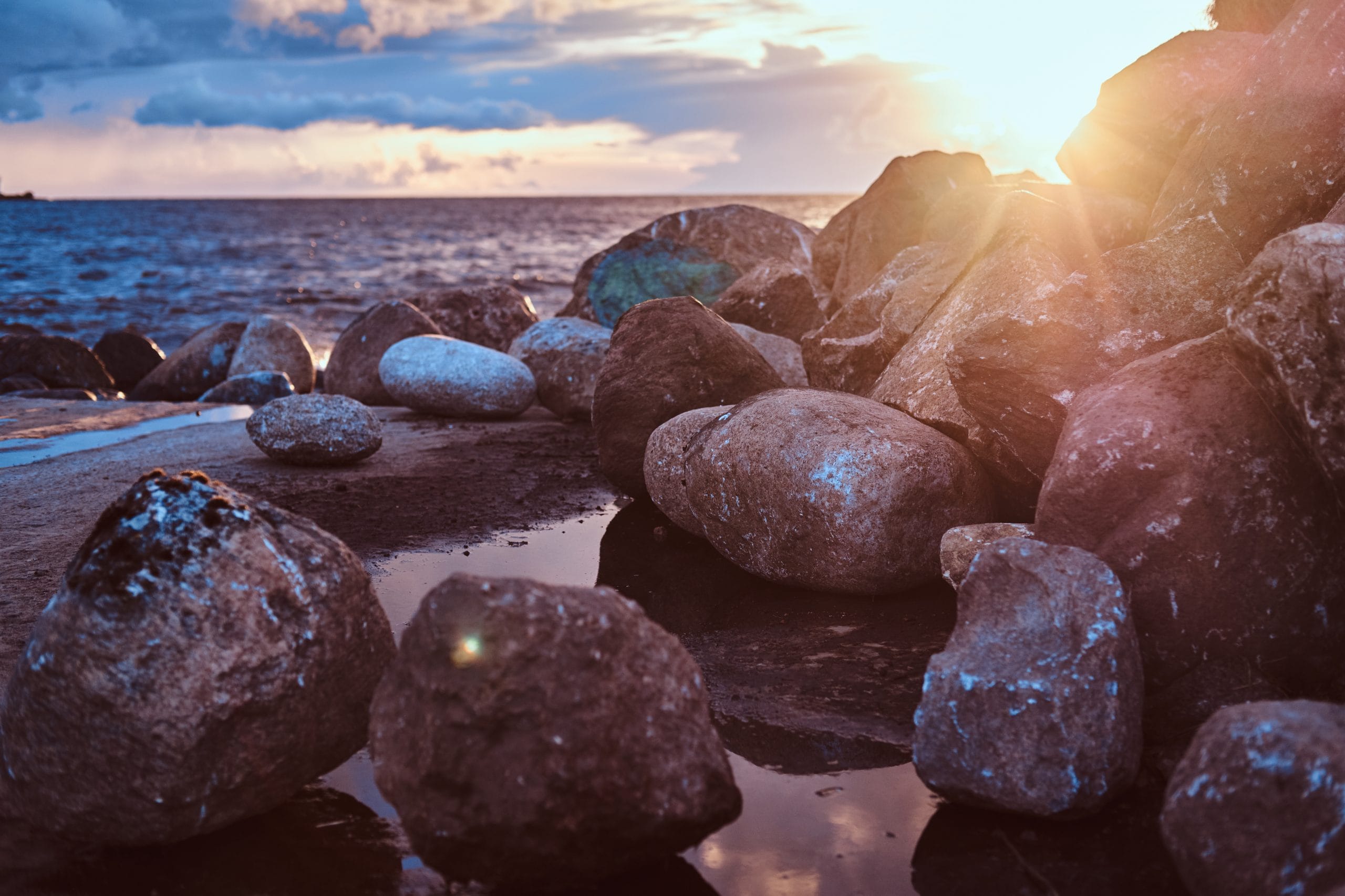 Beautiful seaside with stones, against the background of an amazing bright sunset.